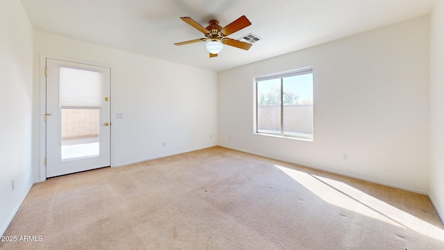 spare room featuring visible vents, light colored carpet, and a ceiling fan