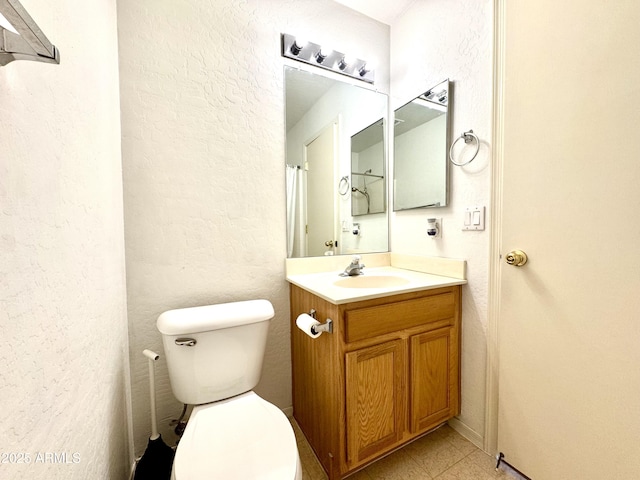 bathroom featuring toilet, vanity, and a textured wall