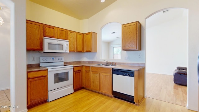 kitchen with visible vents, light countertops, light wood-type flooring, white appliances, and a sink