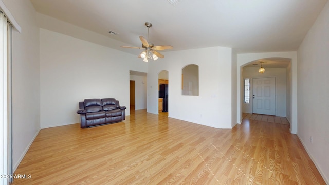 interior space featuring arched walkways, visible vents, light wood-type flooring, and a ceiling fan