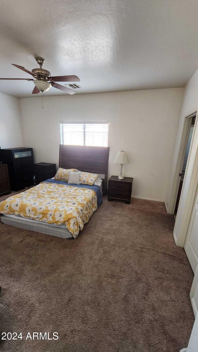 carpeted bedroom featuring ceiling fan and a textured ceiling