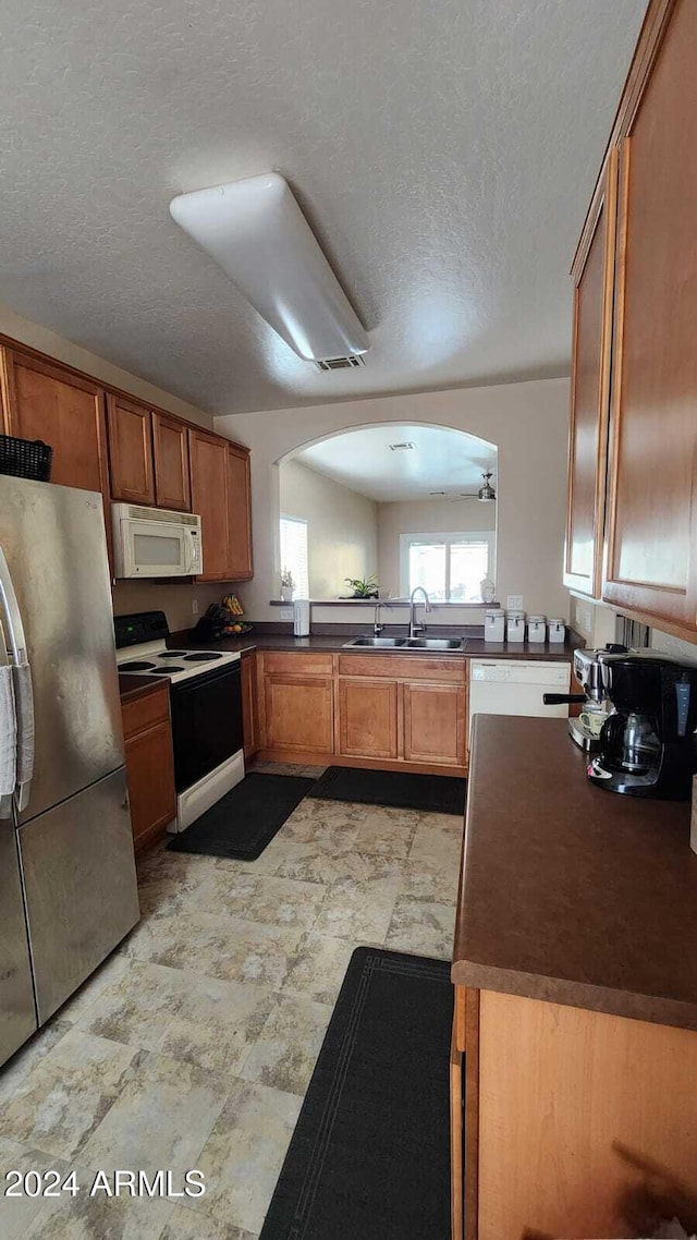 kitchen featuring white appliances, kitchen peninsula, sink, and a textured ceiling