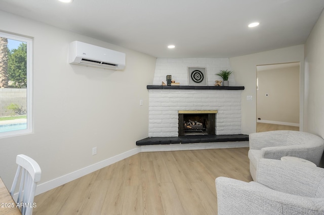 living room with a wealth of natural light, light wood-type flooring, a brick fireplace, and an AC wall unit