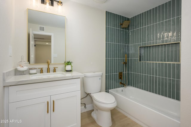 full bathroom featuring hardwood / wood-style flooring, tiled shower / bath, vanity, and toilet