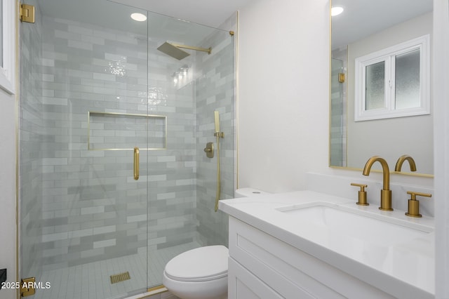 bathroom with vanity, a shower with door, and toilet