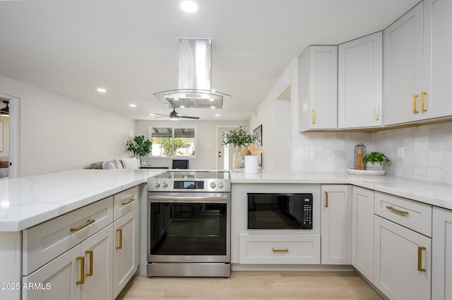 kitchen featuring stainless steel electric stove, black microwave, island exhaust hood, kitchen peninsula, and light stone countertops