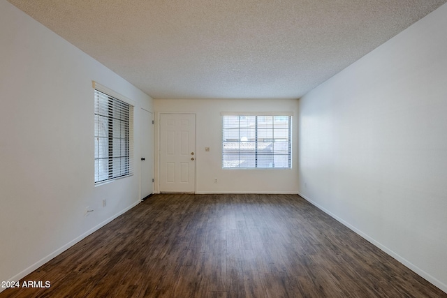 empty room with dark hardwood / wood-style flooring and a textured ceiling