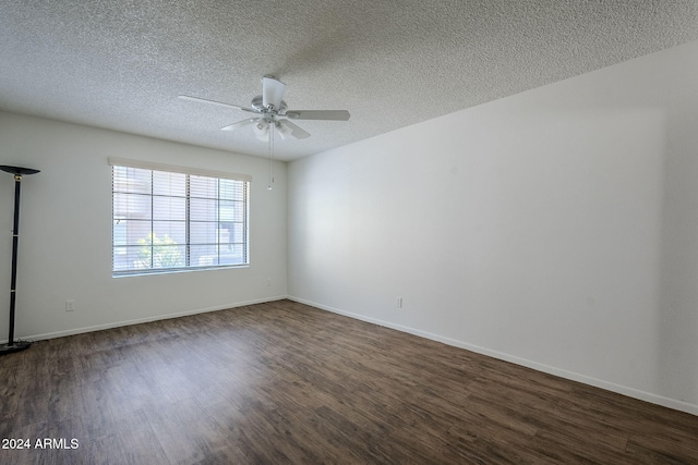 empty room with ceiling fan, dark wood-type flooring, and a textured ceiling