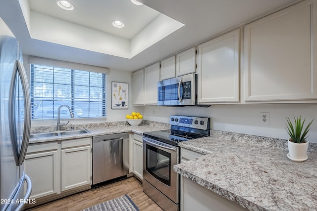 kitchen featuring appliances with stainless steel finishes, light hardwood / wood-style floors, white cabinetry, and sink