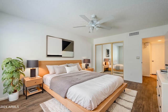 bedroom with a textured ceiling, ceiling fan, a closet, and dark hardwood / wood-style floors