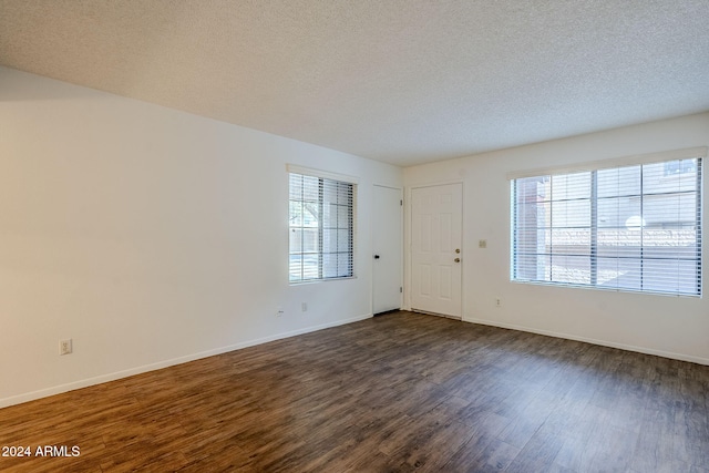 unfurnished room with a textured ceiling and dark hardwood / wood-style floors