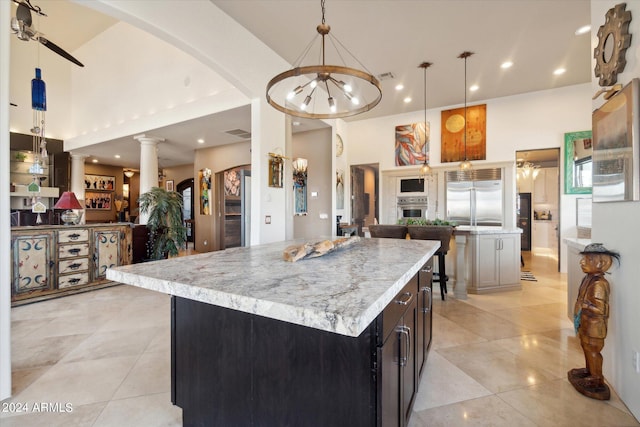 kitchen featuring pendant lighting, a high ceiling, ornate columns, appliances with stainless steel finishes, and a kitchen island