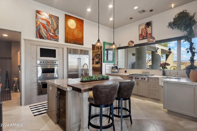 kitchen with sink, hanging light fixtures, gray cabinets, stainless steel appliances, and beverage cooler