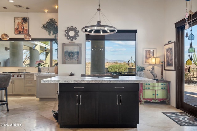 kitchen featuring pendant lighting, a center island, light stone counters, and an inviting chandelier