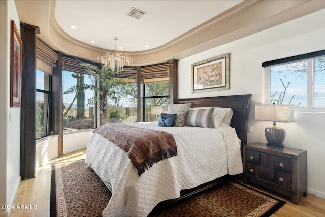 bedroom with light hardwood / wood-style flooring and an inviting chandelier