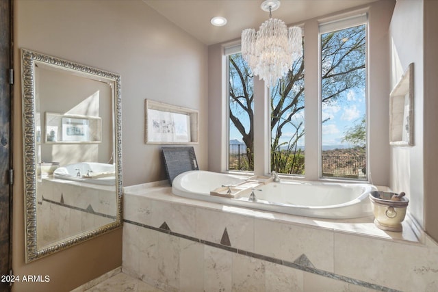 bathroom featuring a notable chandelier, a wealth of natural light, and tiled bath