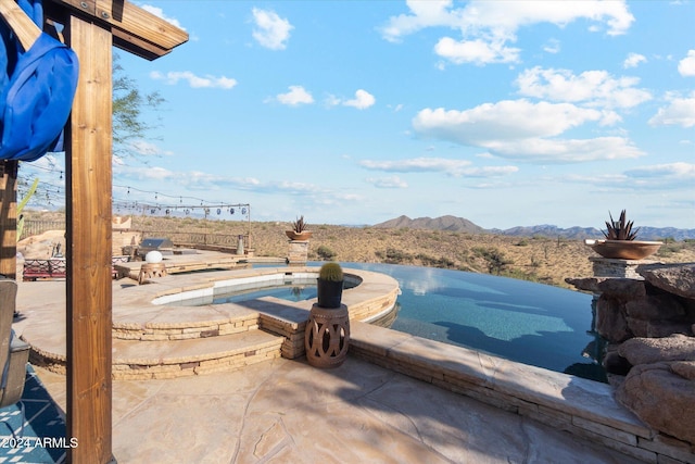 view of patio / terrace with a mountain view and an in ground hot tub