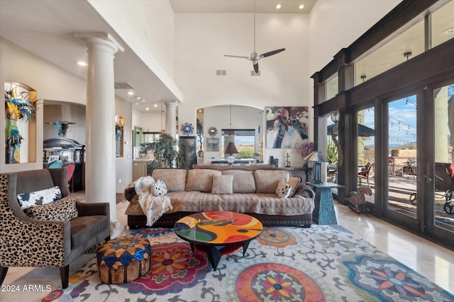 living room with ceiling fan, a towering ceiling, and ornate columns