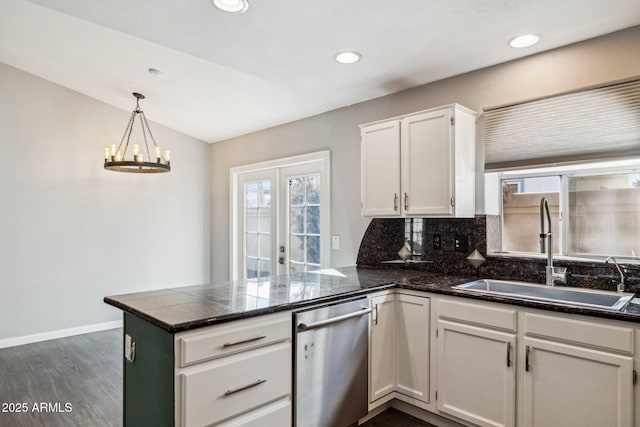 kitchen with decorative backsplash, white cabinets, a sink, dishwasher, and a peninsula