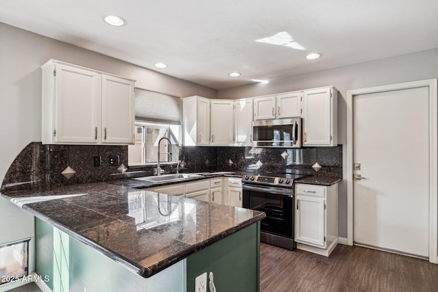 kitchen featuring dark wood finished floors, white cabinets, a peninsula, stainless steel appliances, and a sink