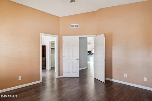 unfurnished bedroom featuring dark wood-style floors, high vaulted ceiling, visible vents, and baseboards