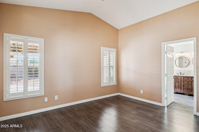 unfurnished room featuring a sink, baseboards, vaulted ceiling, and dark wood finished floors