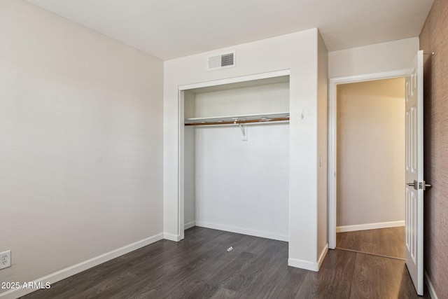 unfurnished bedroom featuring a closet, dark wood finished floors, visible vents, and baseboards