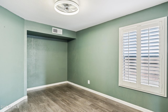 unfurnished room featuring visible vents, baseboards, and wood finished floors