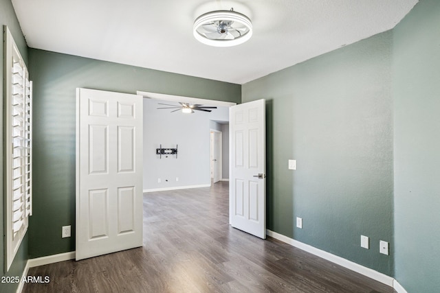 unfurnished room with baseboards, dark wood finished floors, and a ceiling fan