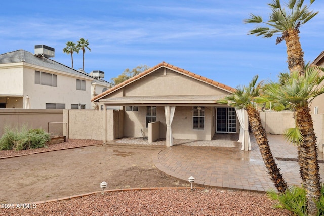 back of property with central AC unit, a patio, a tile roof, fence private yard, and stucco siding