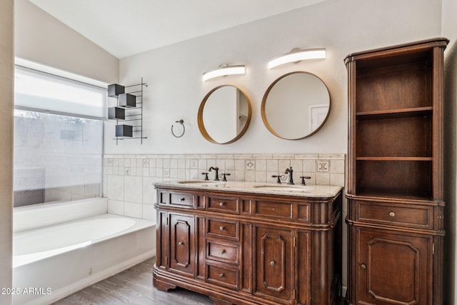 bathroom with wood finished floors, a sink, and tile walls