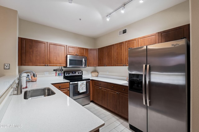 kitchen featuring sink, track lighting, stainless steel appliances, and kitchen peninsula