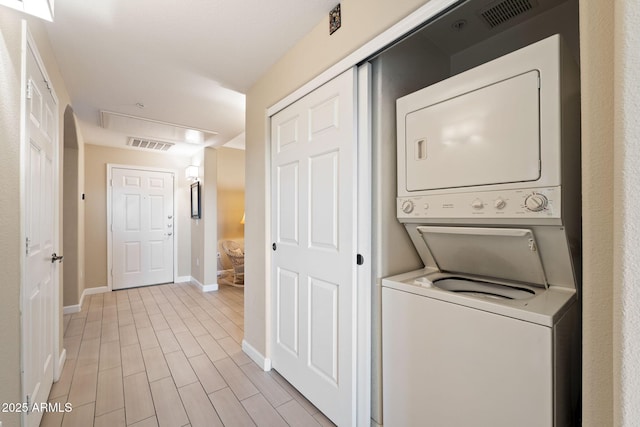 clothes washing area featuring stacked washer and dryer and light hardwood / wood-style floors