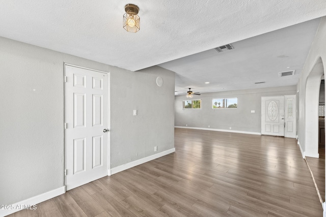 6714 N 26th Dr, Phoenix, AZ 85017 - unfurnished living room with visible vents, ceiling fan, arched walkways, and wood finished floors