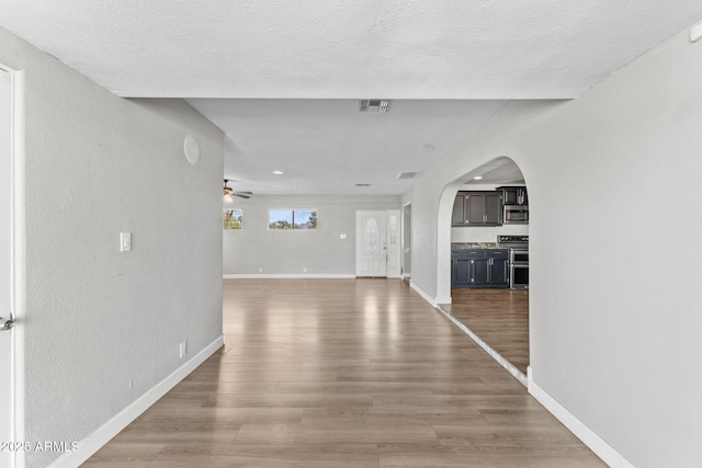6714 N 26th Dr, Phoenix, AZ 85017 - unfurnished living room featuring visible vents, baseboards, arched walkways, a ceiling fan, and wood finished floors
