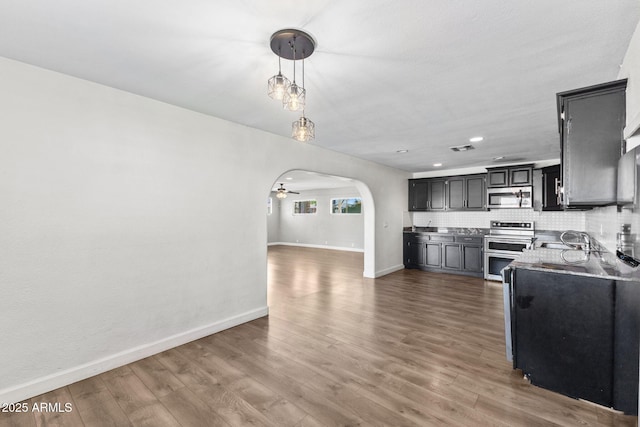 6714 N 26th Dr, Phoenix, AZ 85017 - kitchen with dark cabinets, baseboards, appliances with stainless steel finishes, arched walkways, and wood finished floors