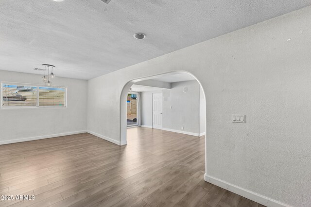 6714 N 26th Dr, Phoenix, AZ 85017 - spare room with baseboards, arched walkways, wood finished floors, and a textured ceiling