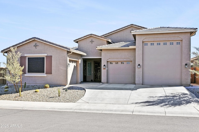 view of front of house featuring concrete driveway, a tile roof, an attached garage, and stucco siding