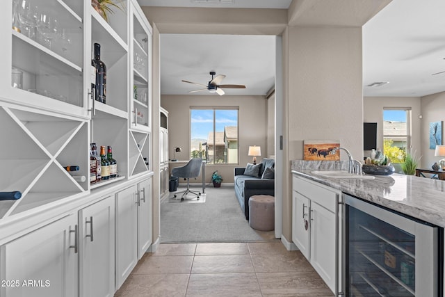 kitchen featuring white cabinets, sink, light colored carpet, and beverage cooler