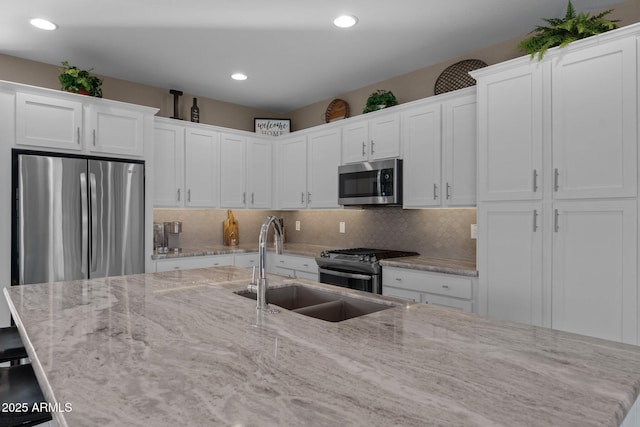 kitchen featuring tasteful backsplash, sink, white cabinets, and appliances with stainless steel finishes