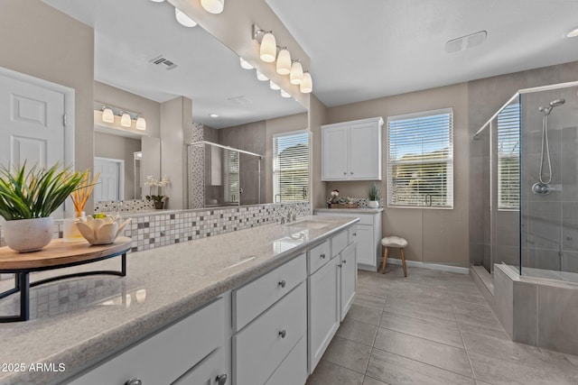 bathroom with tile patterned flooring, vanity, an enclosed shower, and tasteful backsplash