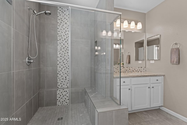 bathroom with a tile shower, decorative backsplash, tile patterned flooring, and vanity