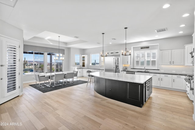 kitchen with a spacious island, hanging light fixtures, a healthy amount of sunlight, and high end refrigerator