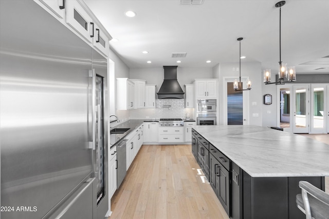 kitchen featuring appliances with stainless steel finishes, pendant lighting, custom exhaust hood, white cabinets, and a large island