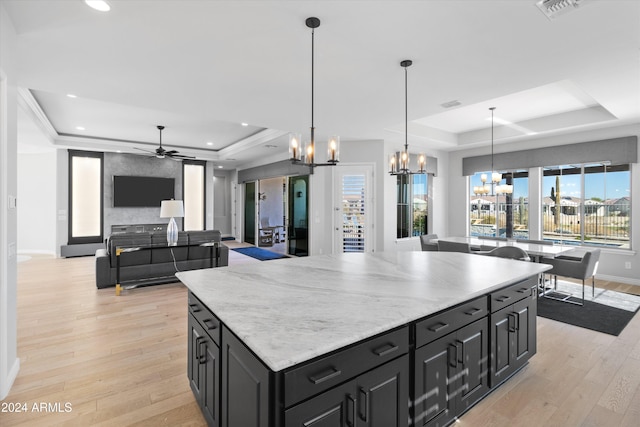 kitchen featuring hanging light fixtures, light hardwood / wood-style flooring, and a tray ceiling