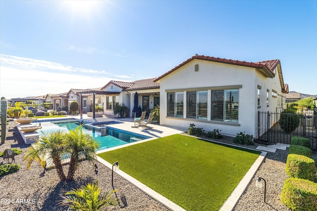 rear view of house with a lawn, a fenced in pool, and a patio area