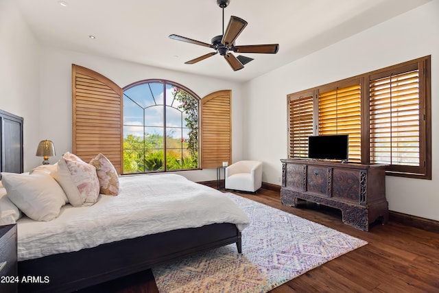 bedroom with ceiling fan, dark wood-type flooring, and multiple windows