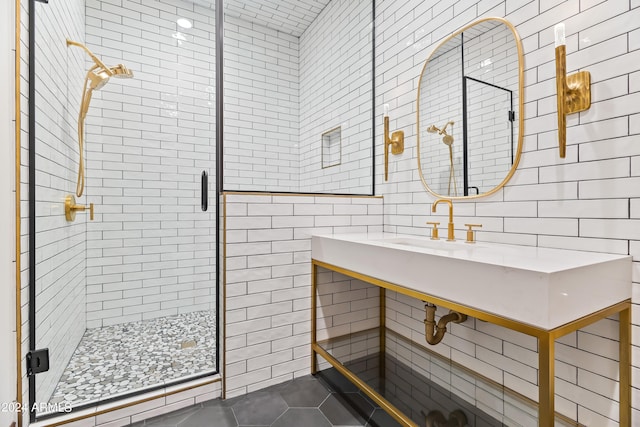 bathroom featuring tile patterned flooring, a shower with shower door, tile walls, and sink