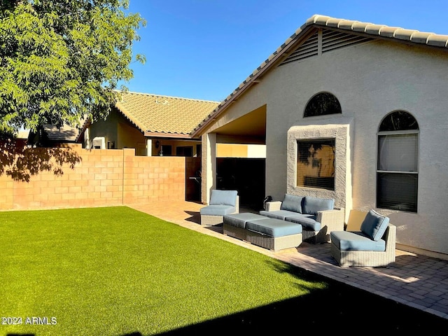 rear view of house with an outdoor living space, a patio area, and a lawn