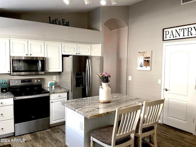 kitchen with a center island, appliances with stainless steel finishes, a kitchen breakfast bar, light stone countertops, and white cabinets